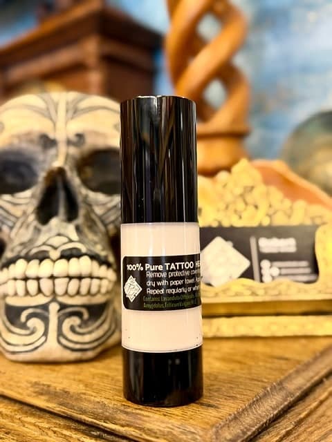 A bottle of the studio's 100% pure tattoo healing oil on a wooden shelf